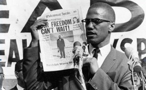 Malcolm X brandissant un exemplaire de Muhammad Speaks, journal de la NOI.
