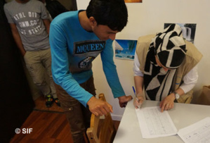 Des réfugiés accueillis dans un foyer du Secours Islamique France (SIF) finalisent leur inscription avant qu’on leur attribue une chambre. (Photo © SIF)