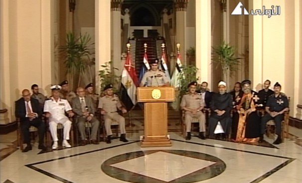 Discours à la nation du général al-Sissi devenu président élu à 98 %, entouré de personnalités militaires, politiques et religieuses, notamment Mohamed El-Baradei (Prix Nobel de la paix, nommé vice-président le 9 juillet mais qui donnera sa démission le 14 août), le cheikh d’Al-Azhar Ahmed El-Tayeb et le pape copte Tawadros II. (Image du 3 juillet 2013, extraite de la télévision d’État égyptienne.)