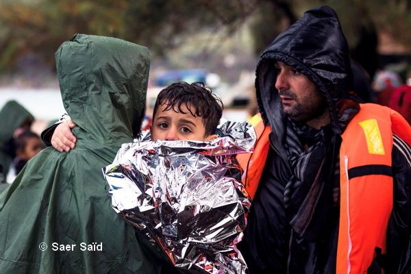Un enfant trempé, dans une couverture de survie, se réchauffe dans les bras de son père. Lesbos (Grèce), octobre 2015. © Saer Said